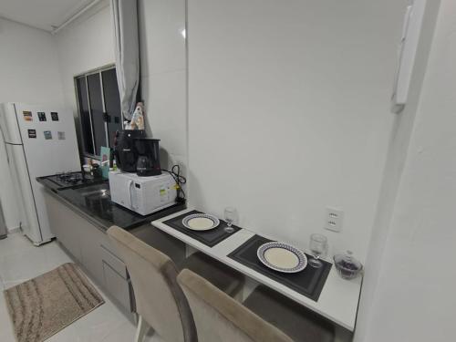 a kitchen with a counter with two chairs and a microwave at Studio CG 4, Campo Grande RJ in Estação Inhoaíba