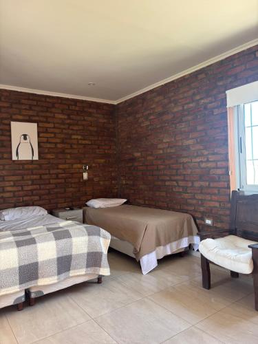 a bedroom with two beds and a brick wall at Posada Patagonia San Juan in Pocito