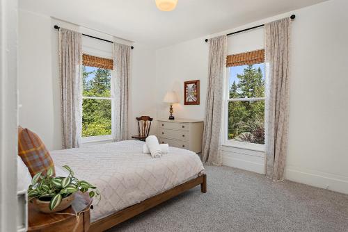 a white bedroom with a bed and two windows at Sebastopol Farmhouse on 3 acres, fiber, kid friendly in Sebastopol