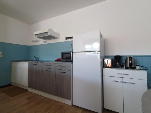La cuisine est équipée d'un réfrigérateur blanc et de placards en bois. dans l'établissement Studio Confortable et Bien Situé – Plages, Port, Animations à Deux Pas - FR-1-476-194, à LʼAiguillon-sur-Mer