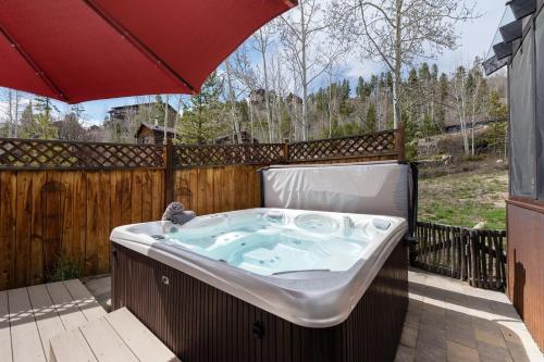 a hot tub on a patio with an umbrella at West Portal Cabin cabin in Grand Lake