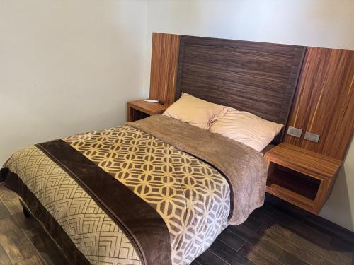 a bedroom with a bed with a wooden headboard at Hotel Los Valles Plus in Creel