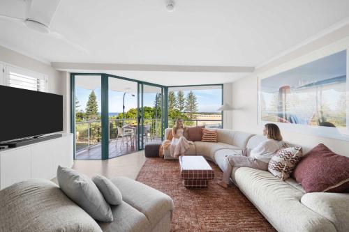 two girls sitting on a couch in a living room at Caprina in Caloundra in Caloundra