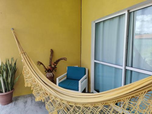 a hammock room with a blue chair and a window at Chalés da Cris in Fortim