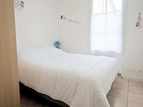 un lit blanc dans une chambre blanche avec une fenêtre dans l'établissement Appartement fonctionnel intra-muros avec cour et garage sécurisé - FR-1-835-1, à Saint-Martin-de-Ré