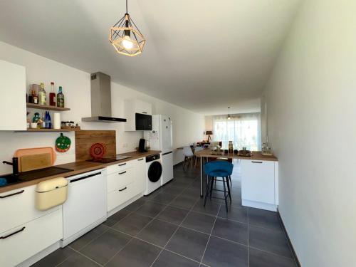 une cuisine avec des placards blancs et une table avec une chaise bleue dans l'établissement Maison neuve proche forêt, 2 chambres, parking privatif - FR-1-323-572, à Saint-Jean-de-Monts