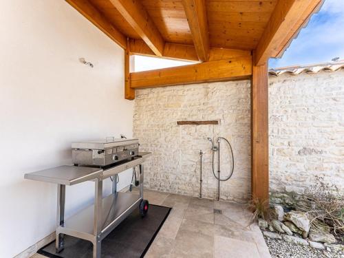 une cuisine extérieure avec un grill et un mur en pierre dans l'établissement Maison 110m² Sud-Ouest avec Terrasse, Patio, et Parking pour 6 Personnes - FR-1-835-12, au Bois-Plage-en-Ré