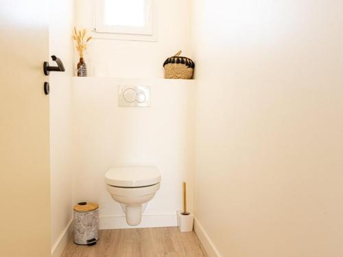 une salle de bain blanche avec toilettes et fenêtre dans l'établissement Maison moderne au Bois-Plage-en-Ré avec jardin - FR-1-835-3, au Bois-Plage-en-Ré