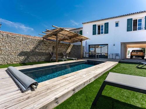 une cour arrière avec une piscine et une maison dans l'établissement Maison moderne au Bois-Plage-en-Ré avec jardin - FR-1-835-3, au Bois-Plage-en-Ré