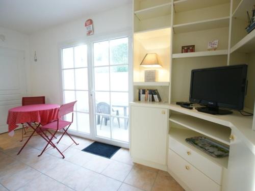 un salon avec une télévision et une table avec une table rose dans l'établissement Appartement Intramuros avec Cour à Saint-Martin-de-Ré - FR-1-835-14, à Saint-Martin-de-Ré