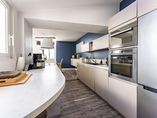 une grande cuisine avec des placards blancs et des murs bleus dans l'établissement Maison familiale à La Noue avec cour privative - FR-1-835-16, à Sainte-Marie de Ré