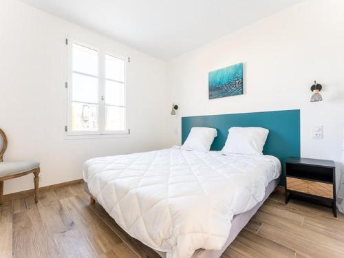 une chambre avec un grand lit blanc avec une tête de lit bleue dans l'établissement Maison moderne avec jardin clos pour 4 pers. - FR-1-835-18, au Bois-Plage-en-Ré