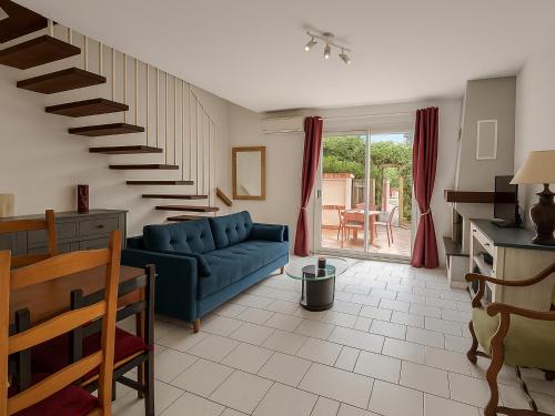 - un salon avec un canapé bleu et un escalier dans l'établissement Maison 6 personnes à 150m de la plage avec terrasse - FR-1-732-107, à Argelès-sur-Mer