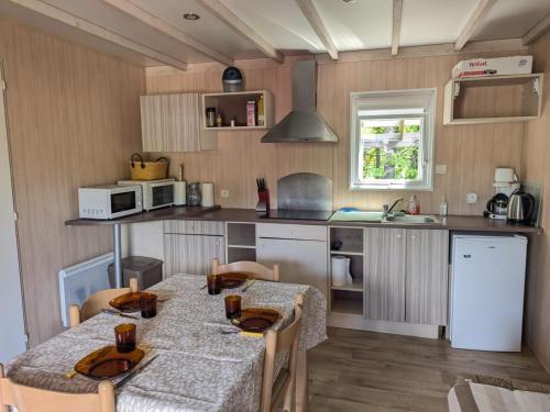 une cuisine avec une table et des chaises et une cuisine avec un évier dans l'établissement Mobil-home moderne dans la nature d'Auvergne - FR-1-814-134, à Égliseneuve-dʼEntraigues