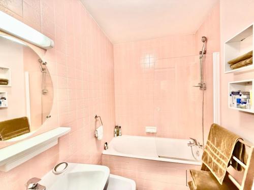 La salle de bains rose est pourvue d'un lavabo et d'une baignoire. dans l'établissement Appartement T2 4 pers, 6ème étage avec WiFi, vue mer - FR-1-197-626, à Les Sables-dʼOlonne