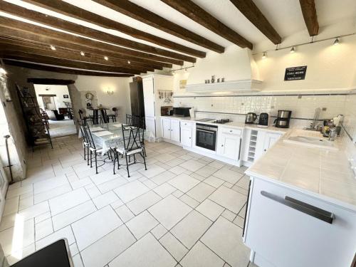 une grande cuisine avec une table et des chaises. dans l'établissement La Gitelière - FR-1-381-624, à Sainte-Catherine-de-Fierbois