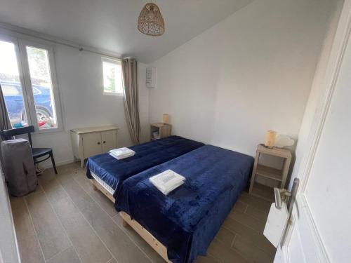 une chambre avec un lit bleu avec deux serviettes dessus dans l'établissement Maison rénovée au calme, animaux admis, 5 personnes - FR-1-476-239, à Saint-Michel-en-lʼHerm