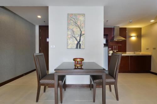 a dining room table with chairs and a picture on the wall at Grand Asoke Suites Boutique Residence in Bangkok