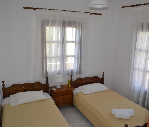 two beds in a room with white walls and windows at Floralia in Karterados