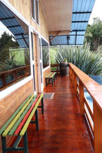a row of benches on a porch with plants at cabañas Arcoíris del lago Nº 2 in Pasto