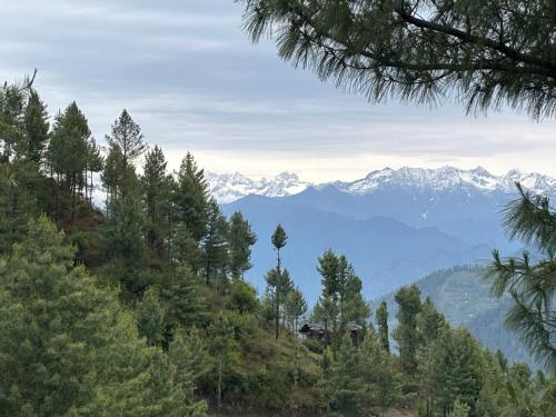 a view of a mountain range with snow capped mountains at Apple Land by Naavagat in Jibhi
