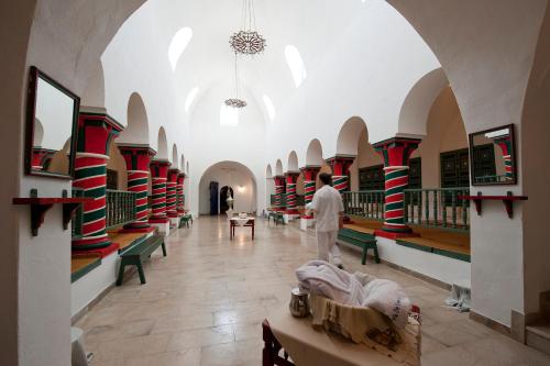 a man walking through a large room with tables and benches at Diar Lemdina Hotel in Hammamet