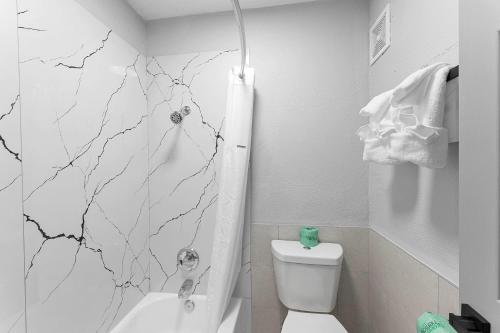 a bathroom with a white toilet and a marble wall at Baymont by Wyndham San Antonio Near Lackland AFB in San Antonio