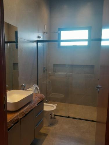a bathroom with a shower with a sink and a toilet at Casa de Campo Paraíso na canastra in Delfinópolis