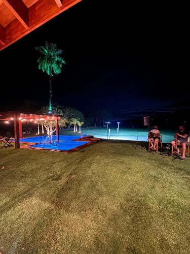 two people sitting on a picnic table at the beach at night at Casa de Campo Paraíso na canastra in Delfinópolis