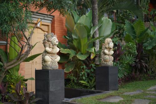 two stone statues are standing in a garden at The Manja Retreat Lovina in Buleleng