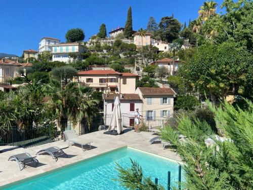 une personne debout à côté d'une maison avec piscine dans l'établissement Calme 2P avec terrasse et jardin, parking et piscine - FR-1-196-382, à Menton