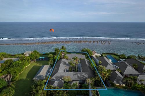 an orange parachute flying over a house and the ocean at Karang Saujana in Uluwatu