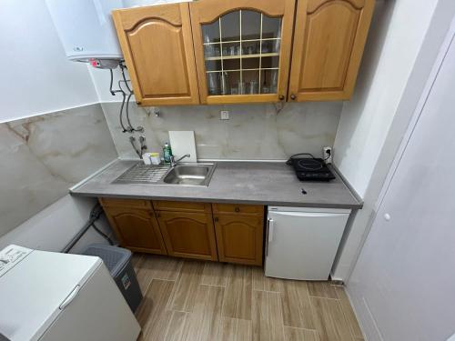 una pequeña cocina con fregadero y armarios de madera. en Stan Na Dan Ninić, en Loznica