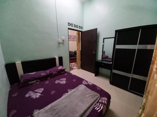 a bedroom with a bed with purple sheets and a mirror at Homestay DC 1 - wifi, netflix in Shah Alam