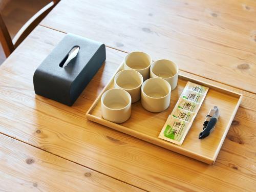 a wooden table with a tray with four cups and a knife at Mission Hills Hotel in Minano