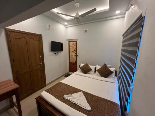 a bedroom with two beds and a tv on the wall at Confident Residency in Guruvāyūr