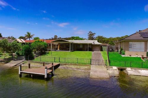 a house on the water with a boat in the water at Seabreeze on Ibis in Sussex inlet