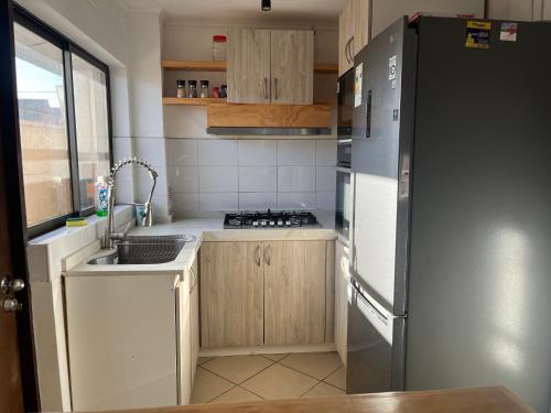 a small kitchen with a refrigerator and a sink at CASA CERCA AERODROMo in Curicó