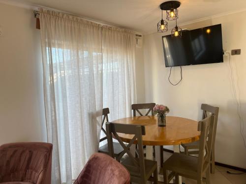 a dining room table with chairs and a television on the wall at CASA CERCA AERODROMo in Curicó