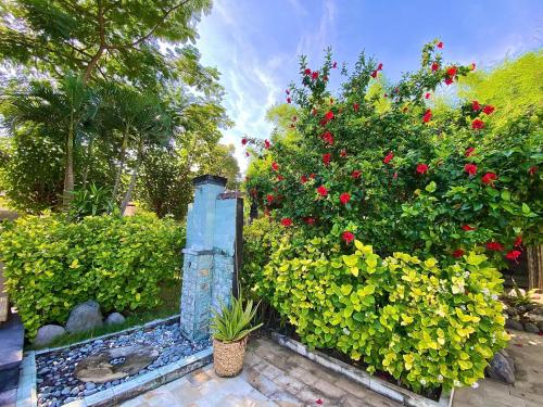 un jardin avec des fleurs et des buissons rouges et jaunes dans l'établissement Sunia Loka Bungalows & Dive Center, à Pemuteran
