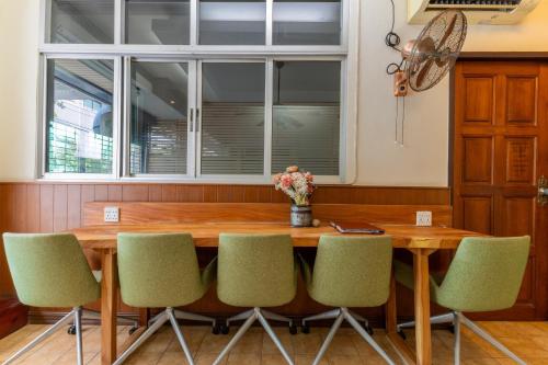 une salle à manger avec une table en bois et des chaises vertes dans l'établissement Calmly Stay Ratchada, à Bangkok