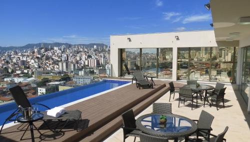 uma varanda com mesas e cadeiras e vista para a cidade em Hotel Beaga Convention Expominas by MHB em Belo Horizonte