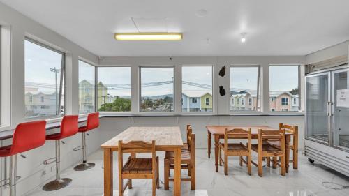 a dining room with a table and chairs and windows at Christchurch Backpackers in Christchurch
