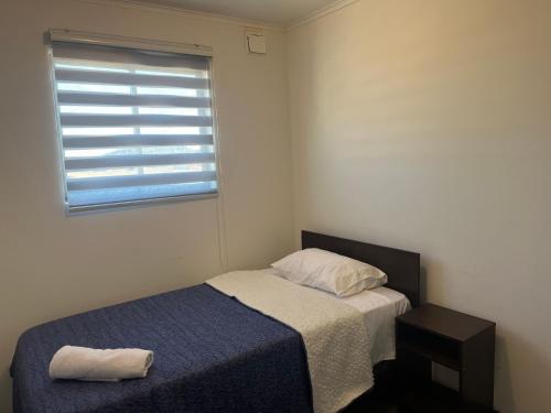 a small bedroom with a bed and a window at CASA CERCA AERODROMo in Curicó