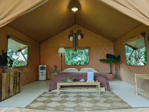 a bedroom in a tent with a bed and a table at Binifarm Tropical Retreat in Cu Chi