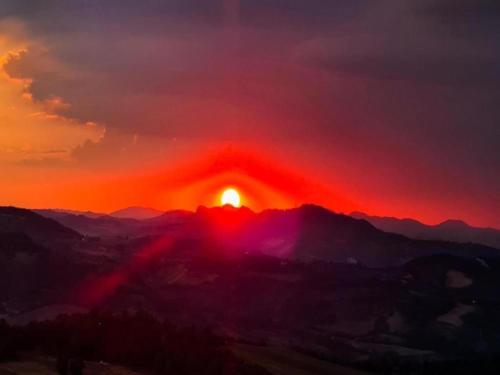 a sunset over a mountain range with the sun setting at Apartment in quiet and green environment with swimming pool in Modigliana
