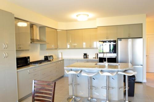 a kitchen with white cabinets and a island with bar stools at Luxury 5 Bed Retreat for 12 with Gourmet Kitchen in Paris