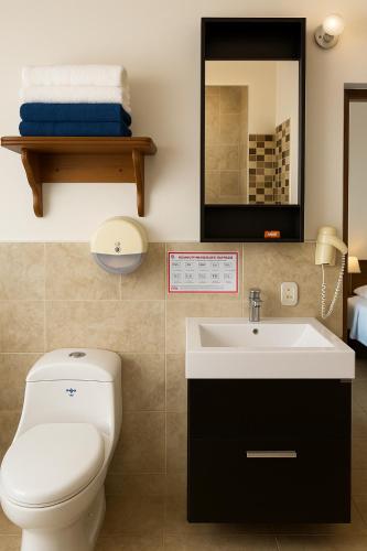 a bathroom with a toilet and a sink and a mirror at Hosteria La Real in Santa Fe de Antioquia