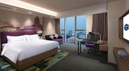 a hotel room with a bed and a desk and a desk at Hampton by Hilton Suzhou XiangCheng in Suzhou
