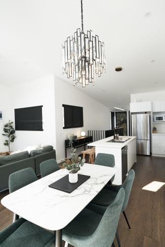 a dining room and living room with a white table and chairs at PISTE LUXURY CHALET - THE PETITE - Oaks Lake Crackenback Resort in Crackenback